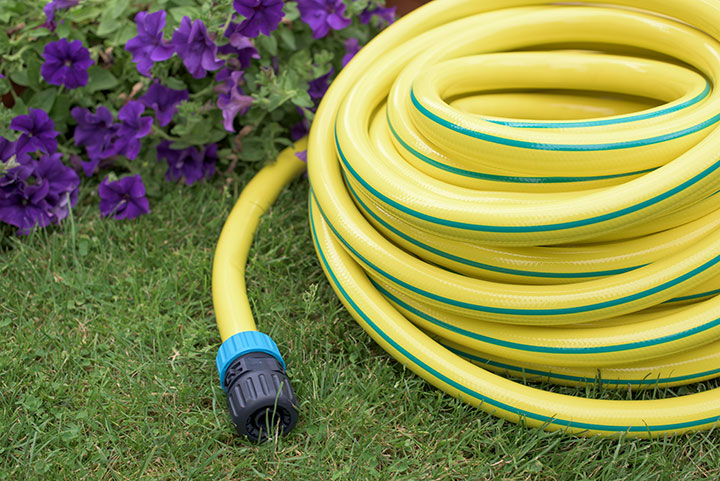 Water Faucet With Rubber Tube Roll In Garden Stock Photo